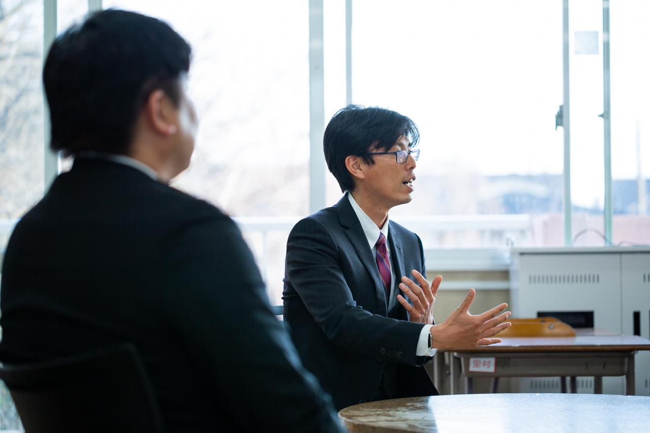 森田先生が手振りを混じえて話してい様子が、塩盛先生の背中越しに見えている