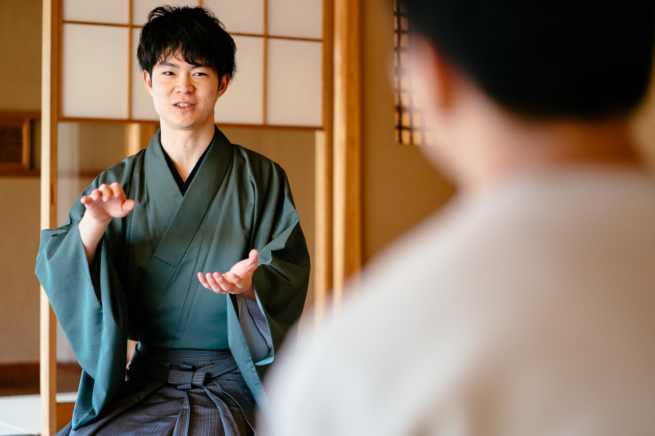 Ryo Iwamoto speaking while gesturing with both hands