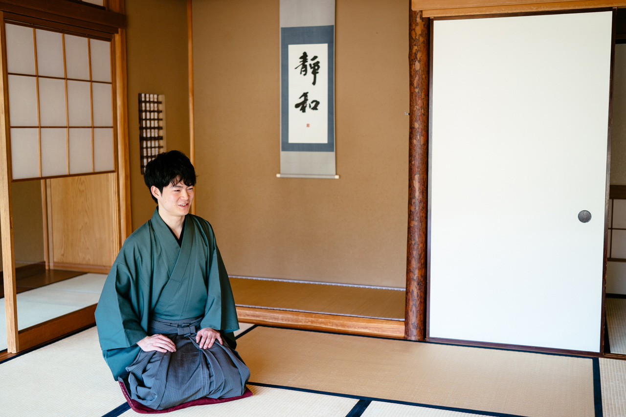 Ryo Iwamoto sitting with his legs holded in the corner of a tatami room in his tea house