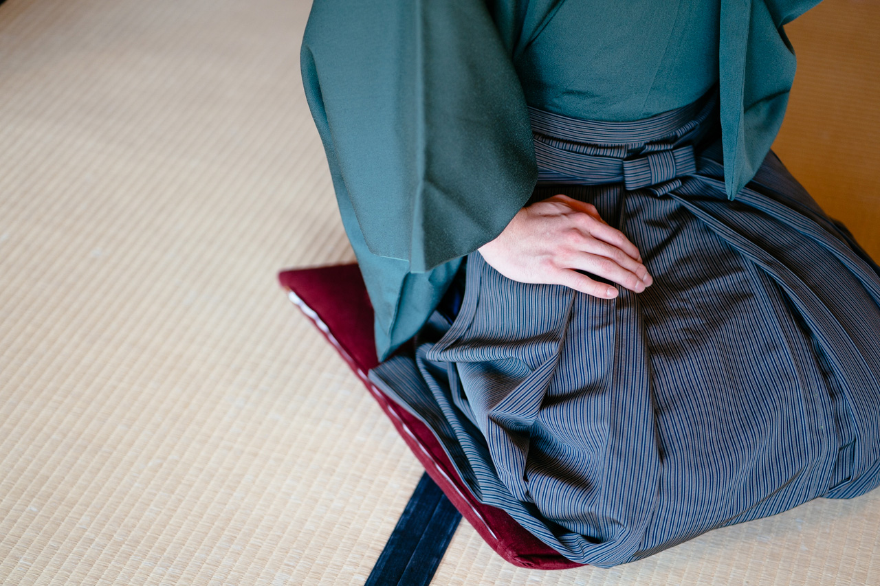 Ryo Iwamoto sitting with his legs folded and his hand on his thigh