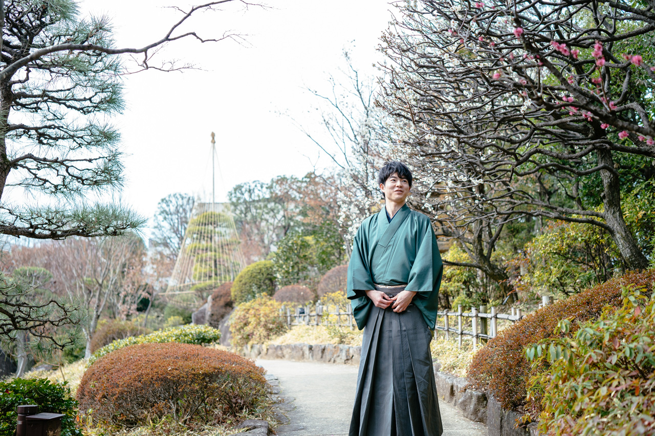 Ryo Iwamoto standing outside in a Japanese garden as the plum trees begin to bloom