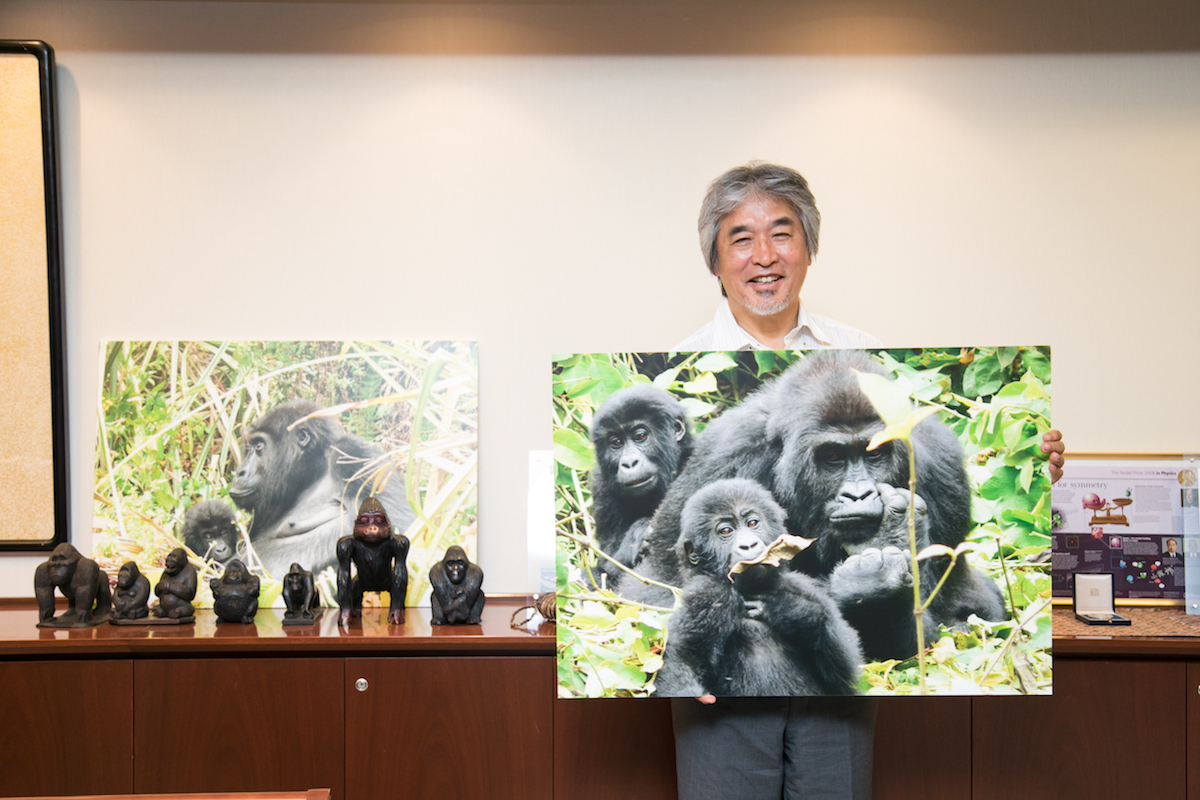 ゴリラの大きな写真を持つ、笑顔の山極さん